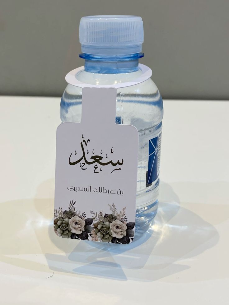 زجاجة مياه بملصق زهري يحتوي على نص عربي، شفافة، 500 مل، مثالية للترطيب.