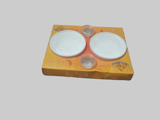 Two white ceramic plates on a yellow box with floral design on a patterned fabric background