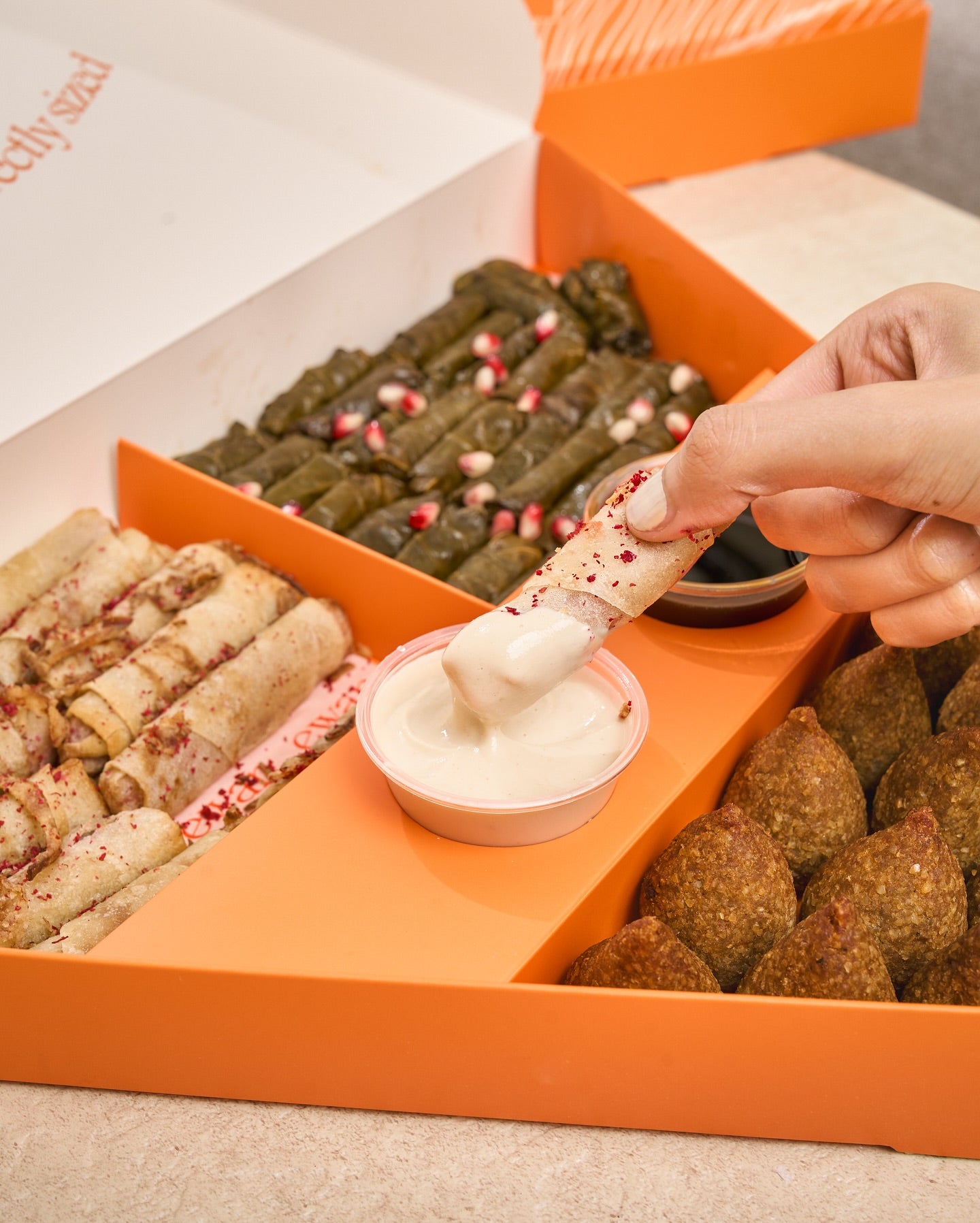 Close-up of removable appetizer dividers and two sauce containers inside catering box