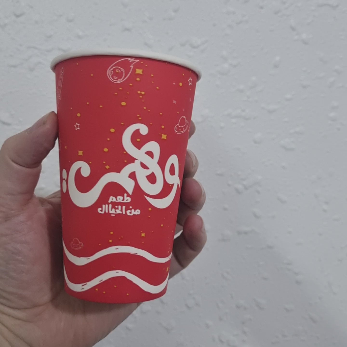 Red disposable paper cup with vibrant design, perfect for hot beverages or party use.